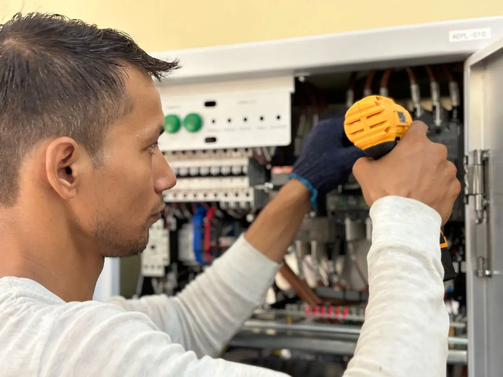 Técnico usando uma furadeira em um quadro elétrico