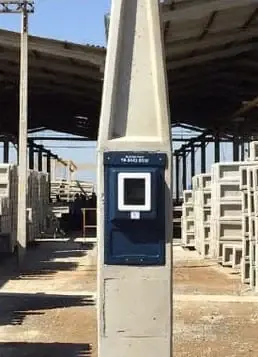 Padrão de entrada com caixa de medição azul fixada em poste de concreto, em um pátio de obra
